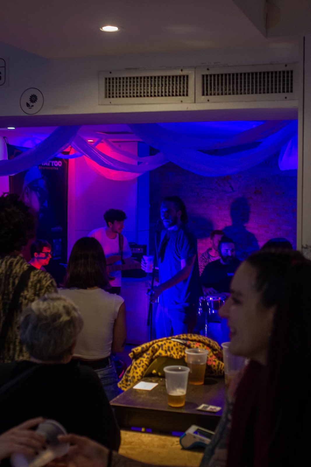 Evento en vivo bañado en luz azul y violeta, con una banda tocando.