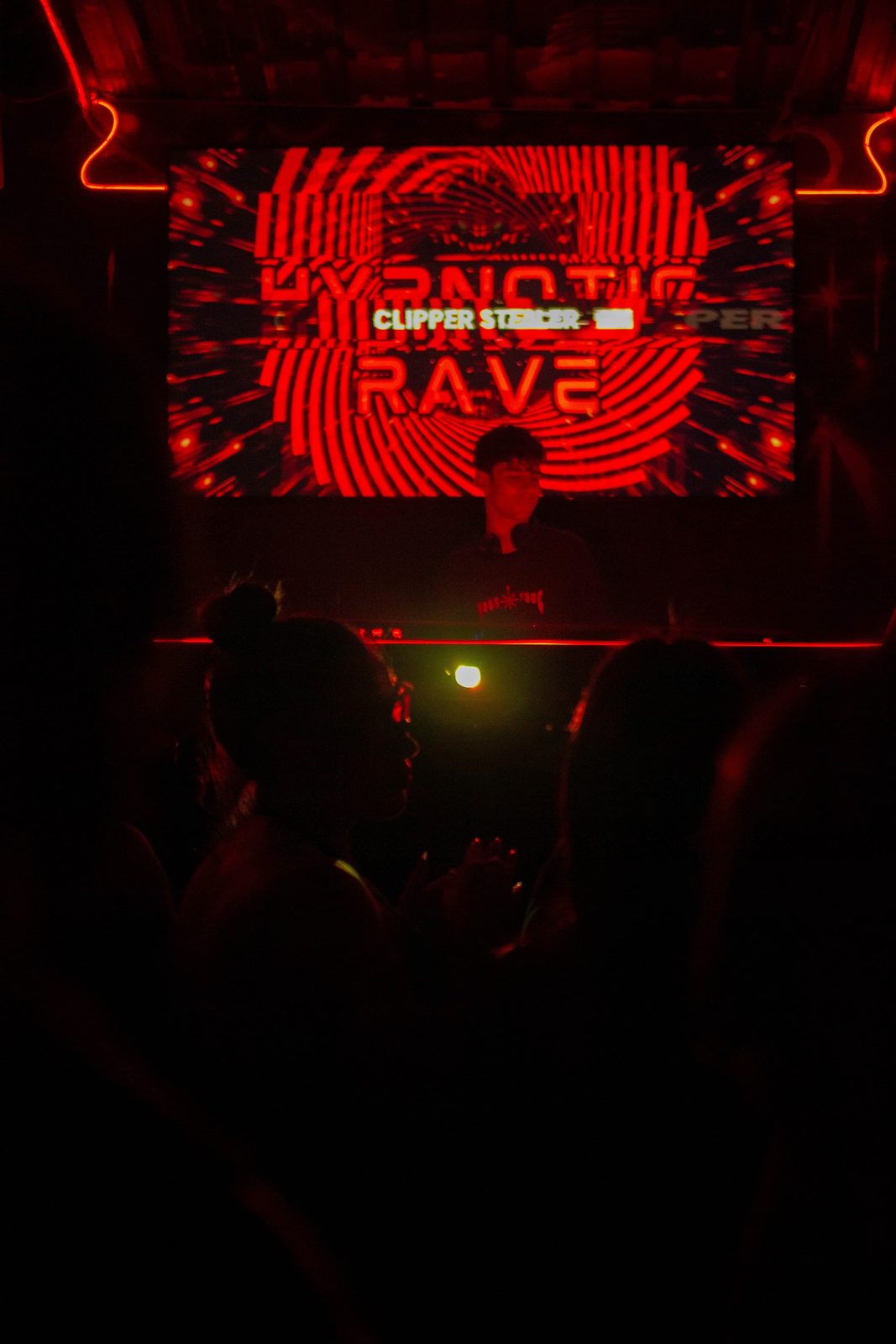 Proyección roja con la leyenda Hypnotic Rave sobre el público a oscuras.